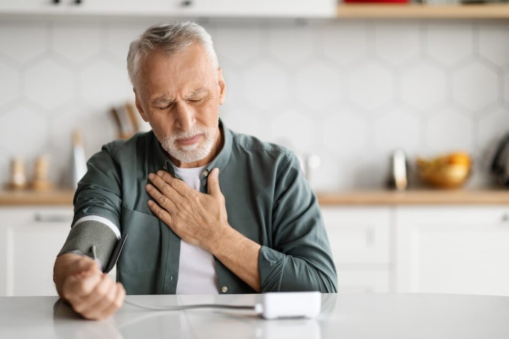Senior Man Feeling Unwell At Home, Checking Blood Pressure With Arm Monitor